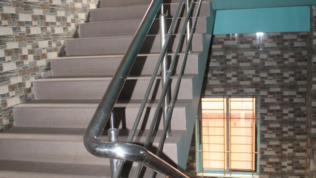 A staircase with metal handrails and a patterned wall. - Akashi Villa Inn (Guwahati)