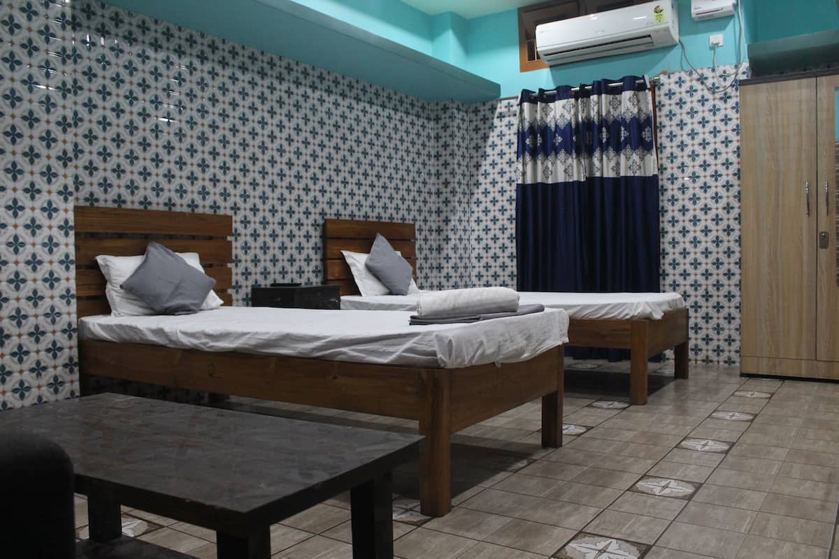 A room with two wooden beds, a small table, and a wardrobe.