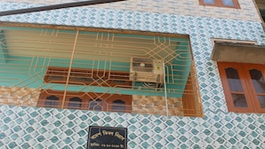 A multi-story building with a patterned facade, multiple windows with orange shutters, and an air conditioning unit on the exterior. - Akashi Villa Inn (Guwahati)