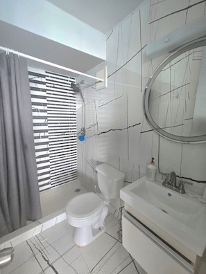 Un baño con inodoro, lavamanos y ducha.