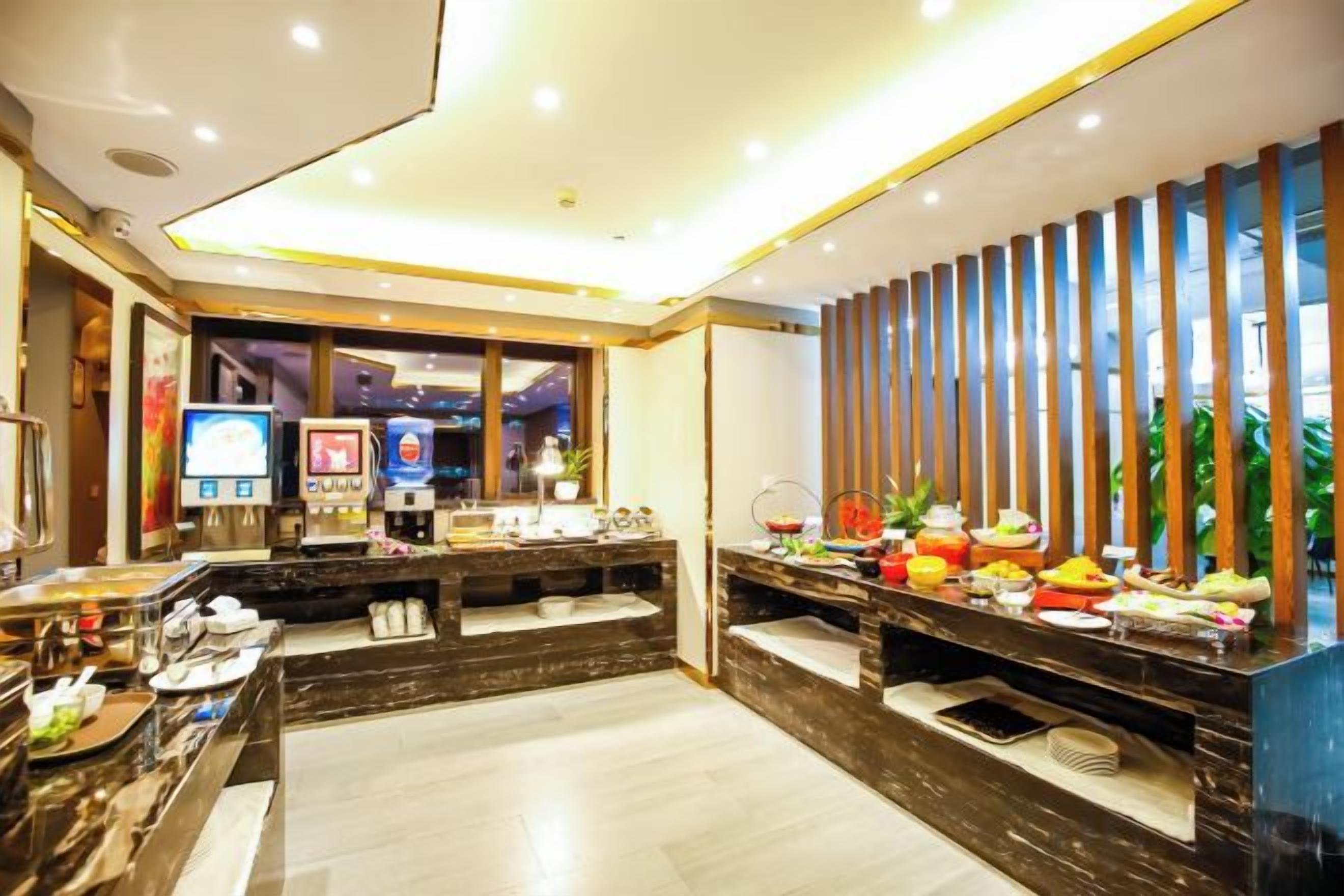 Vestíbulo de hotel con mostrador de recepción, zona de estar y bufé con diversas opciones de comida.