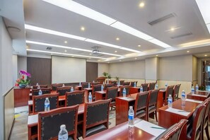 Un salón de conferencias con varias mesas y sillas, equipado con botellas de agua y bolígrafos.
