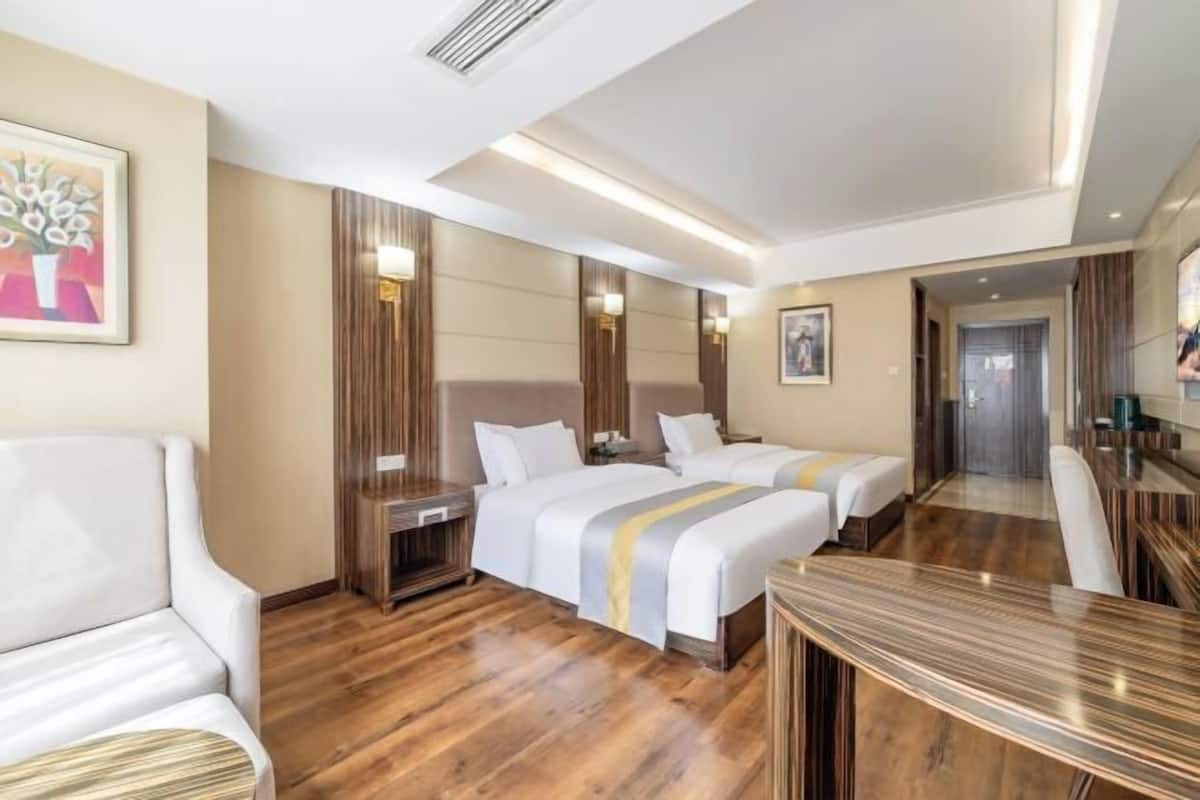 Une chambre d’hôtel avec deux lits, un canapé, un plancher en bois et une table à manger.