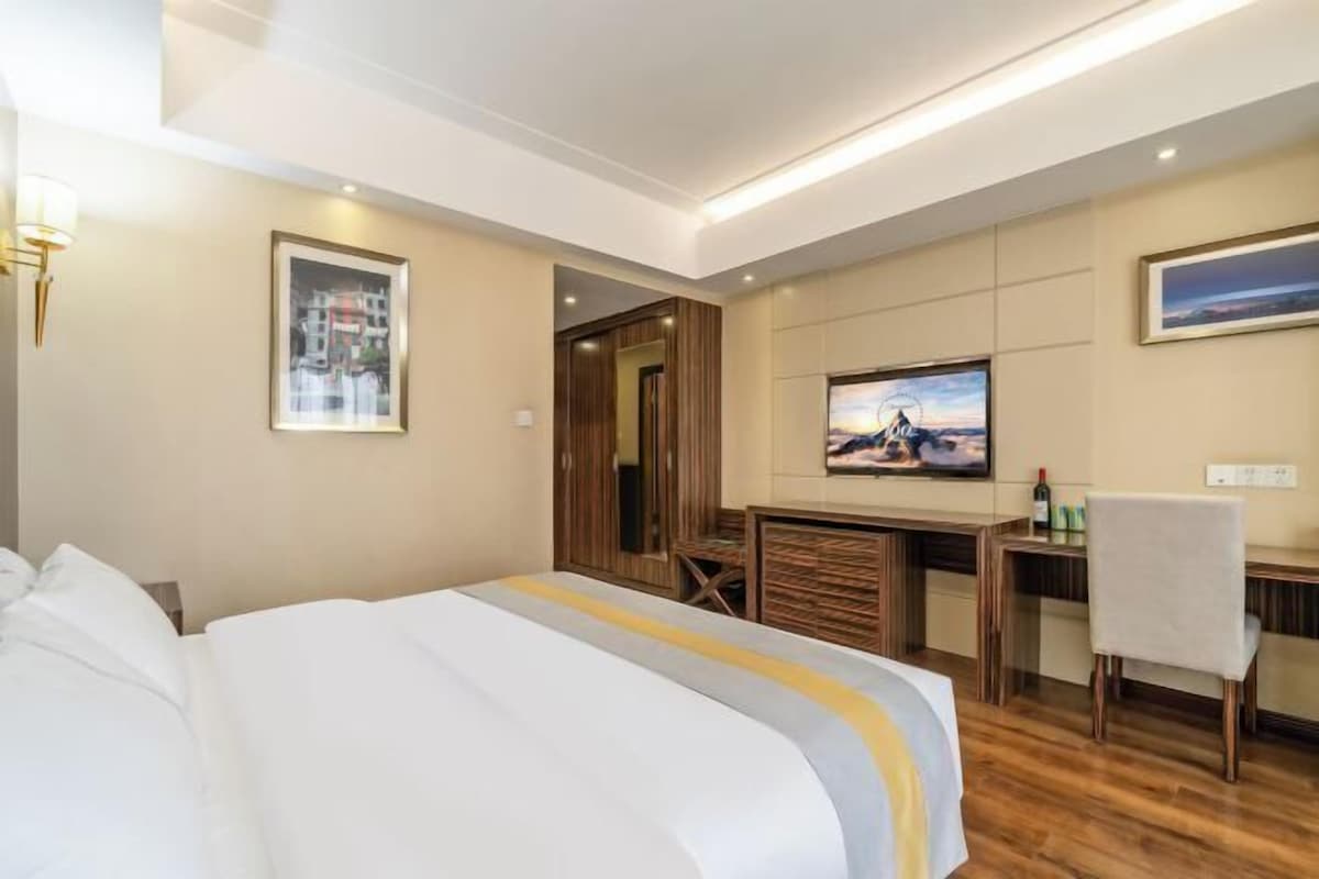 A hotel room with a bed, a desk, a television, and a wardrobe.