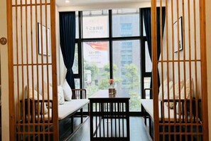 A room with a large window, a sofa, a dining table, and a wooden partition. - Ruihao Yazhi Hotel (Global Center Store) (Chengdu)