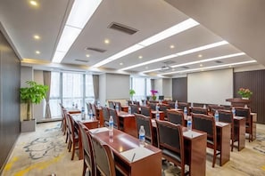A conference room with rows of tables and chairs, a projector screen, and a podium.