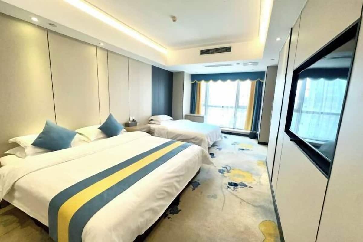 Une chambre d’hôtel avec deux lits, une grande fenêtre et une vue sur l’extérieur.