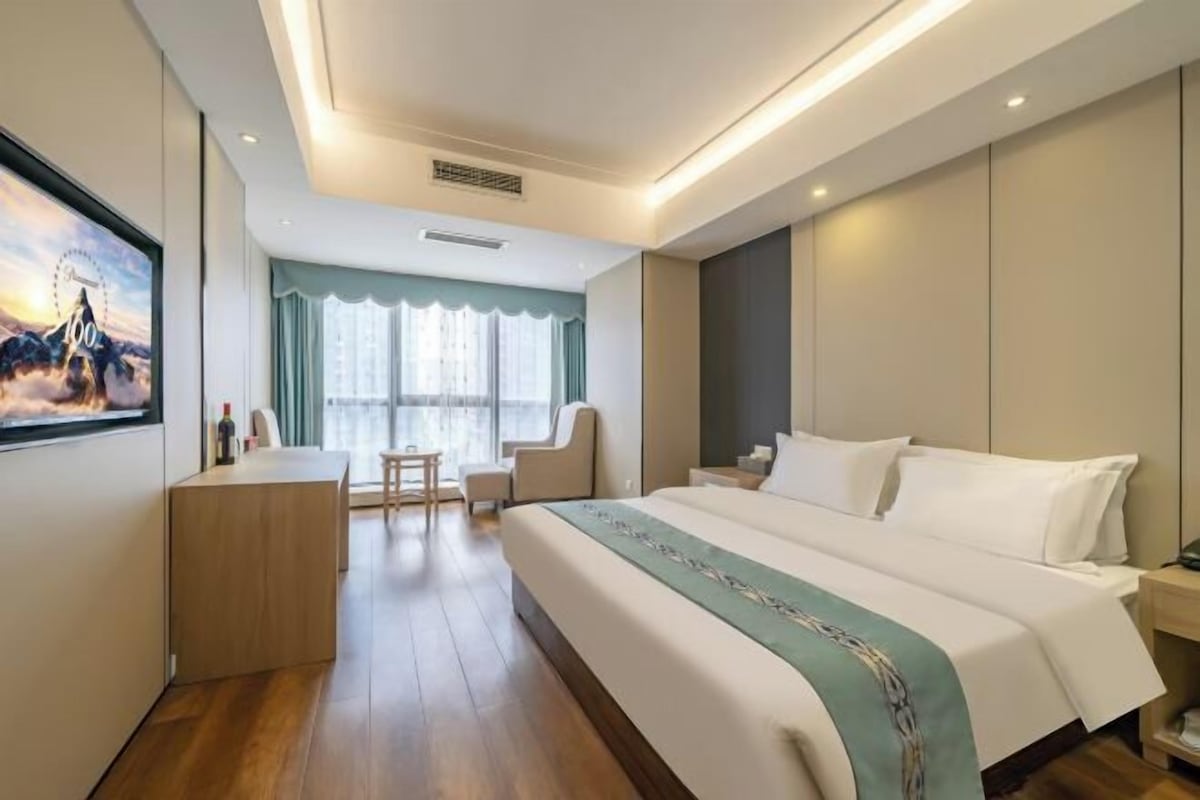 A modern hotel room with a large bed, a desk, and a chair.