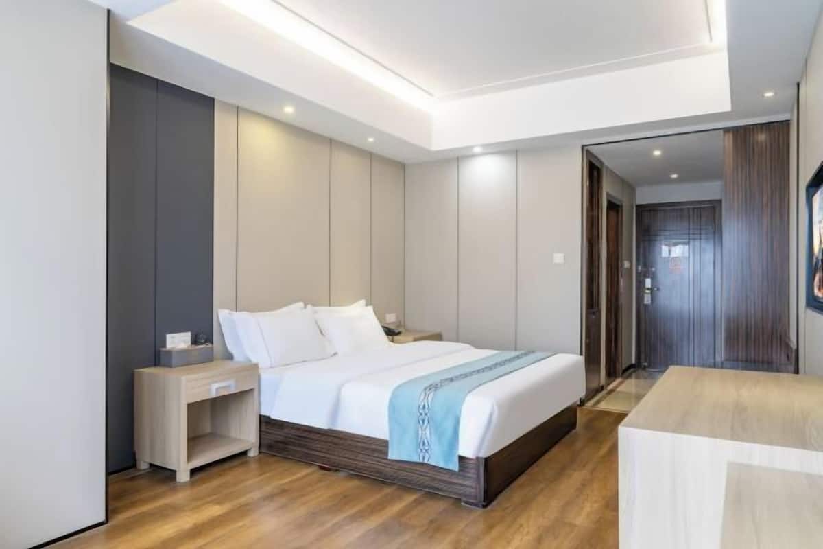 Une chambre d’hôtel moderne avec un grand lit, des tables de chevet, un plancher en bois et un luminaire au plafond.