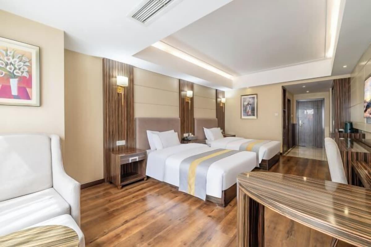 A hotel room with two beds, a sitting area, a dining table, and a large mirror.