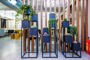 Un interior moderno con listones verticales de madera, estanterías negras con plantas y un extintor.