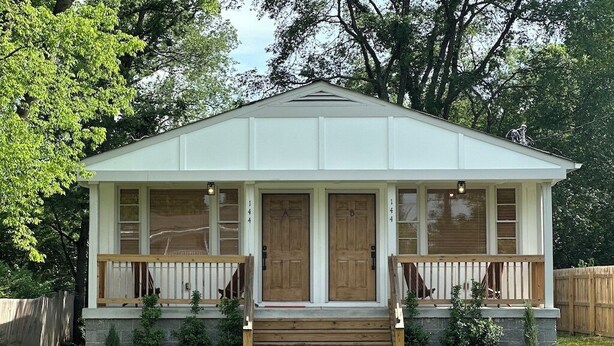A small, single-story house with a front porch, a wooden deck, and a stone foundation. - Escape to Nashville: 15 min to Downtown & BNA, sleeps 4, gated parking! (Madison)