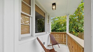 A covered porch with two wooden lounge chairs and a wooden railing. - Escape to Nashville: 15 min to Downtown & BNA, sleeps 4, gated parking! (Madison)