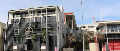 A modern building with a prominent logo, a gated entrance, and a visible sign for a restaurant.