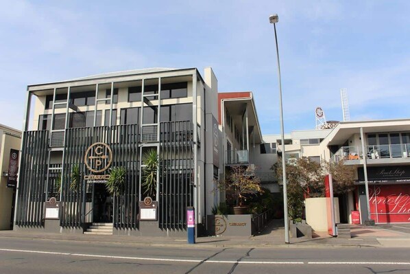 Un bâtiment moderne, doté d’un logo bien visible, d’une entrée sécurisée par un portail et d’une enseigne clairement identifiable pour un restaurant.