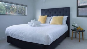 Camera da letto moderna con un letto grande, un comodino e una finestra vista alberi.