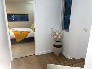 Une chambre à coucher avec un lit, une fenêtre et un vase rempli de fleurs.