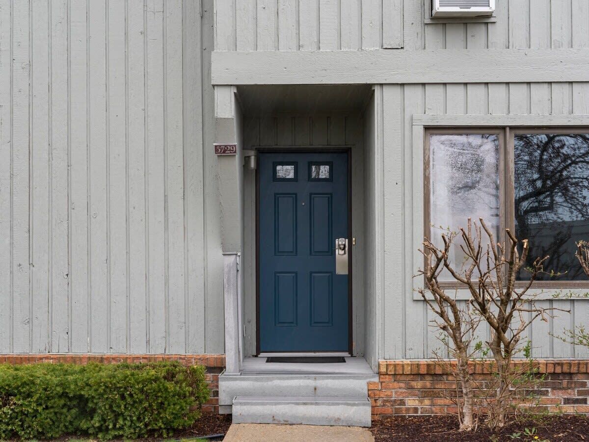A building with a blue door, a small porch, and a window.