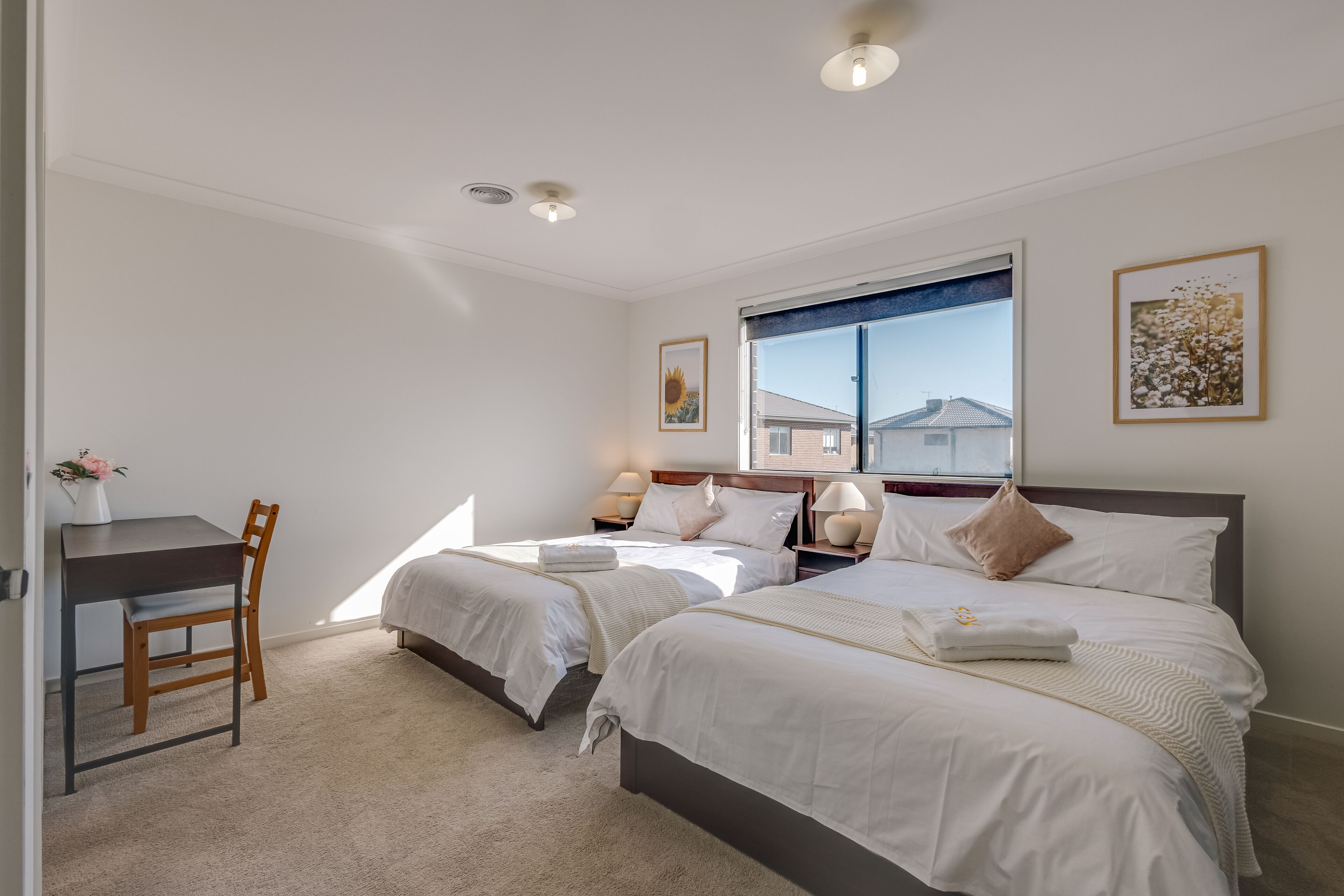 A hotel room with two beds, a desk, and a chair.