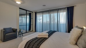 A modern hotel room with a large bed, a sofa, a small table with a plant, and a large window with curtains. - StayAU Newly Cozy Holiday House Tarneit (Tarneit)