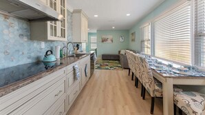 Una cocina con mostrador, armarios y un comedor con sillas y mesa.