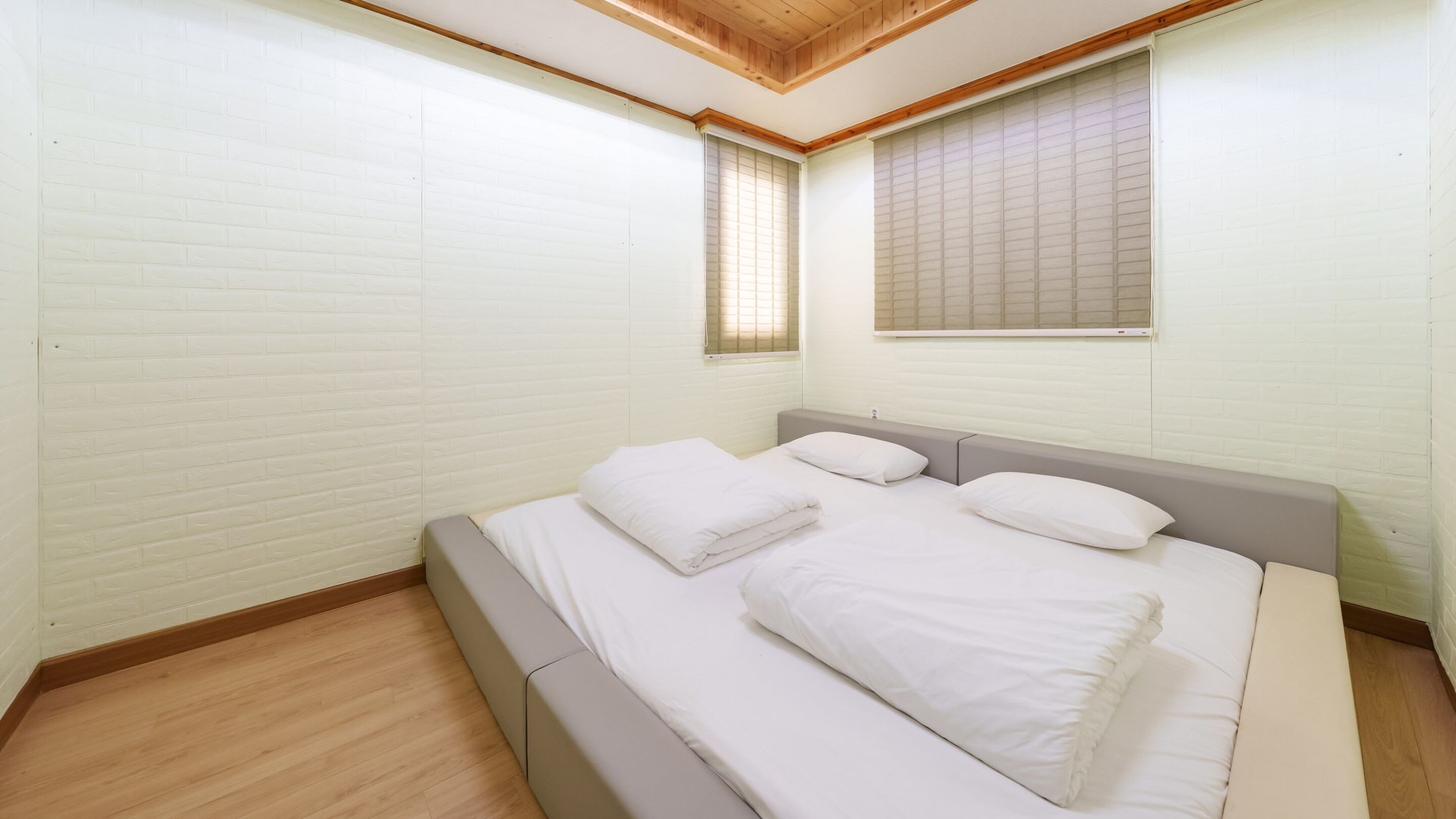 A bedroom with a bed, a window, and a wooden ceiling.