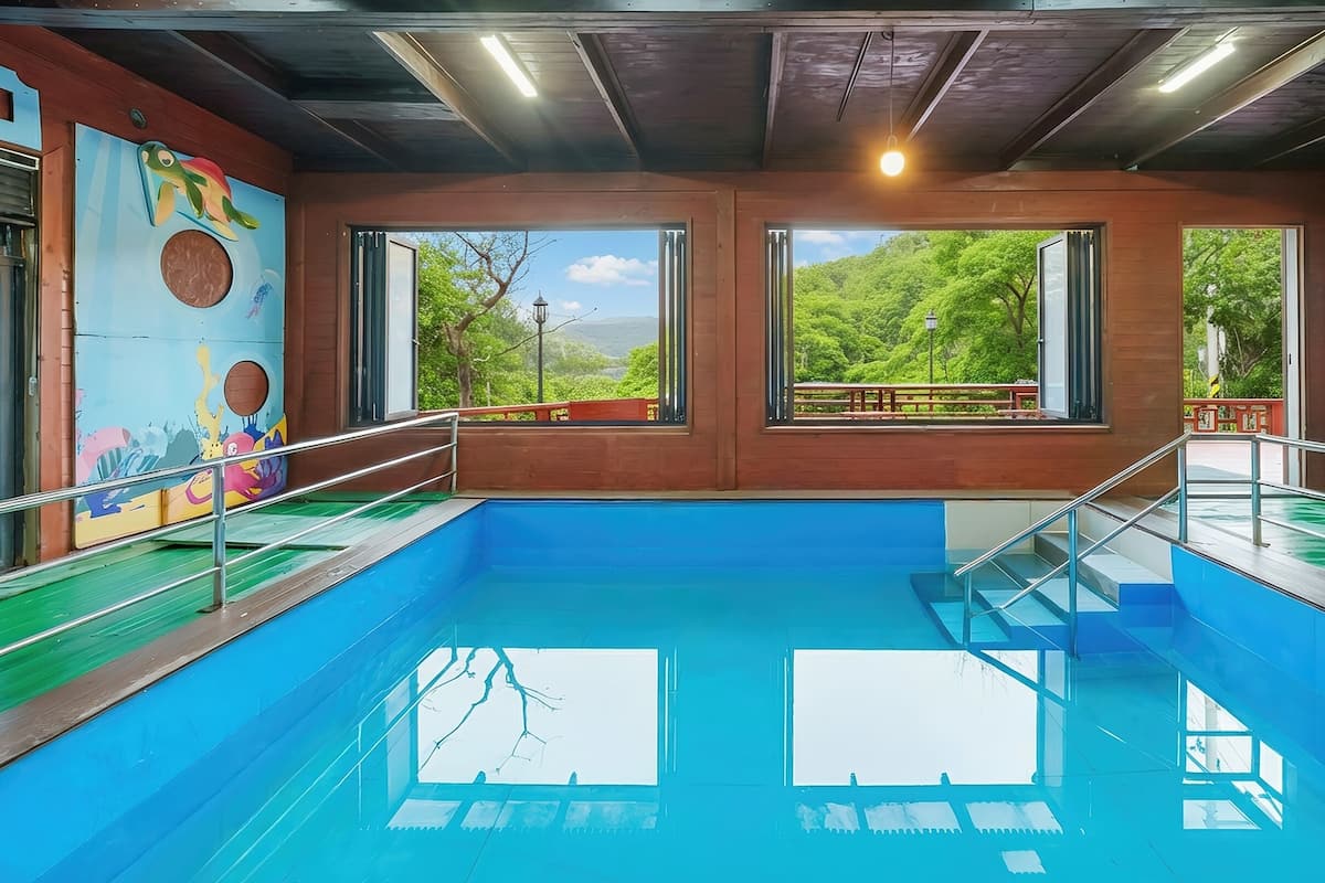 An indoor swimming pool with clear views of greenery outside.