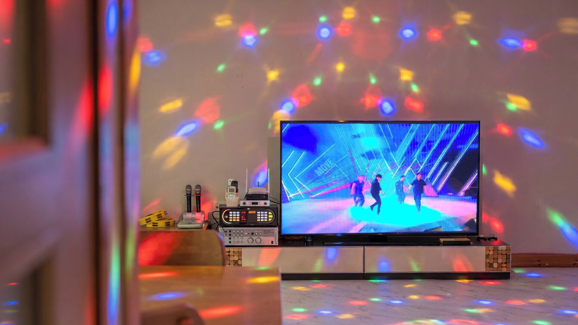 A television displaying a dance performance with a DJ setup in the foreground.