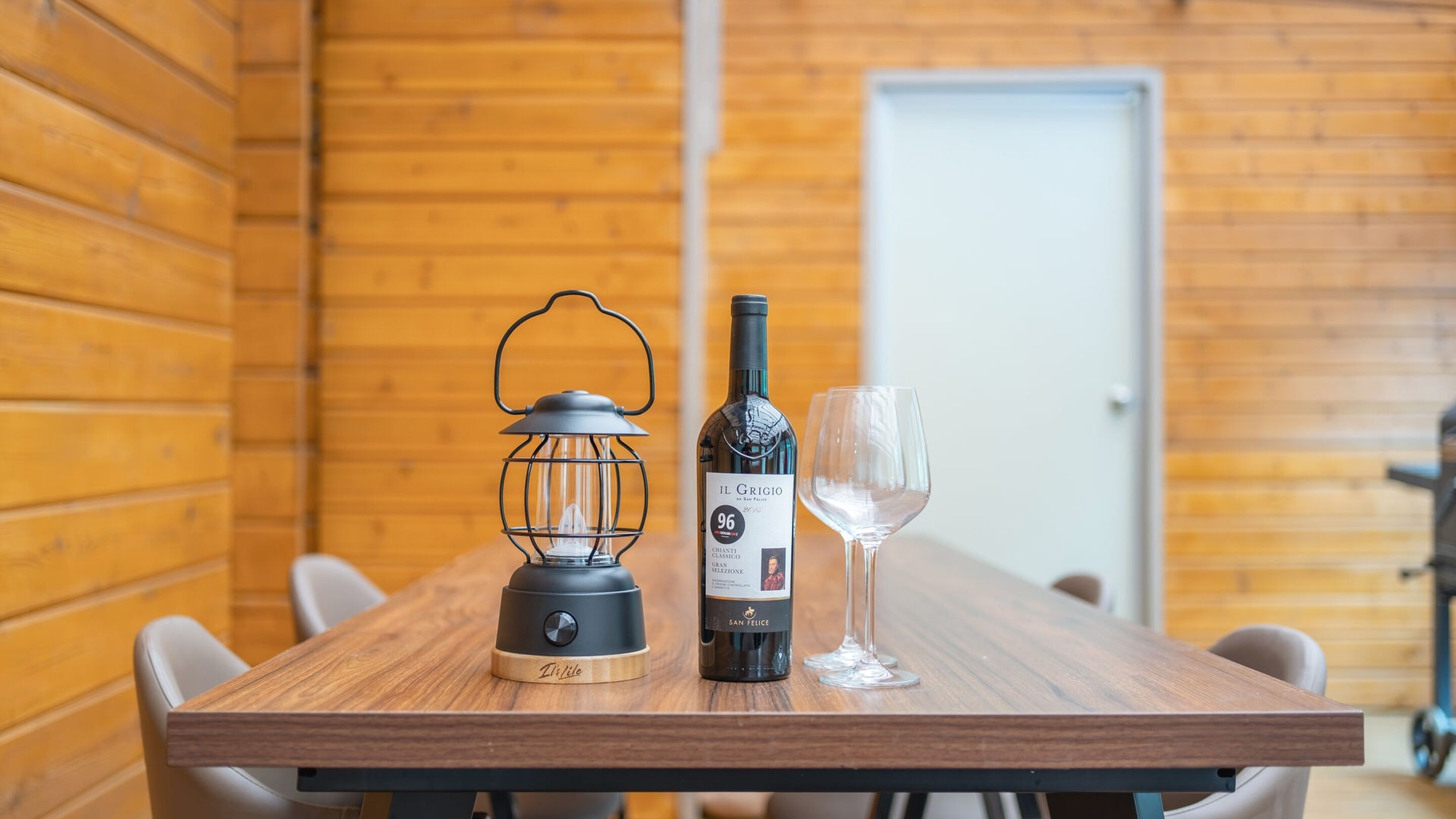 A wooden table with a wine bottle, a wine glass, and a lantern.
