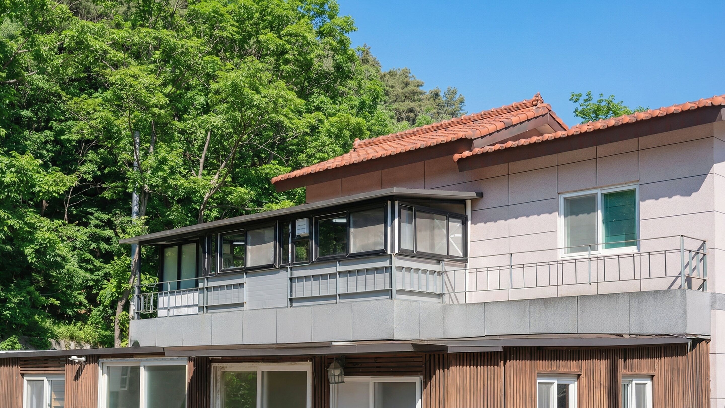 Un edificio di due piani con un balcone al piano superiore, circondato da alberi.