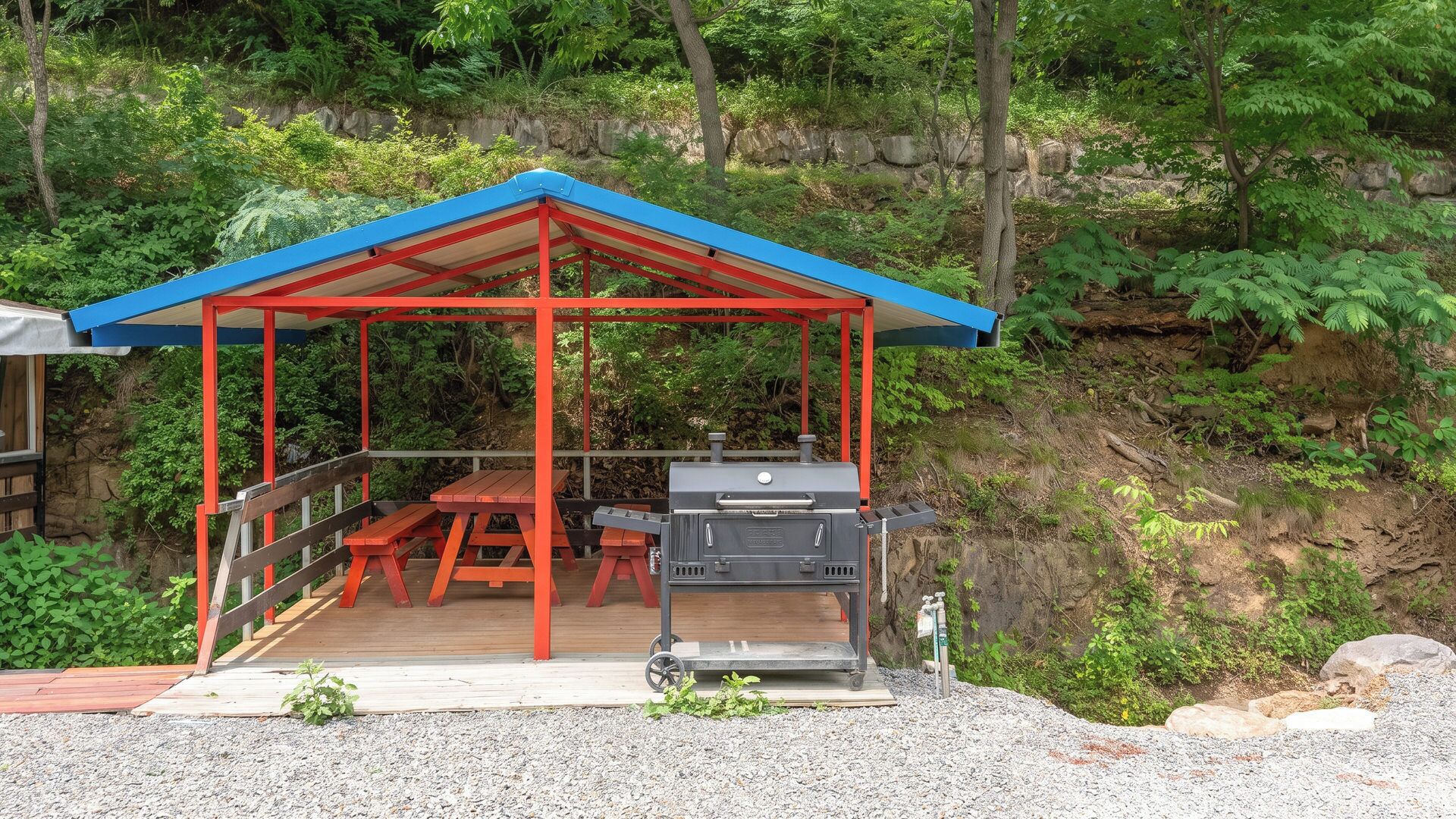 Un espacio al aire libre techado con una parrilla y una mesa de picnic.