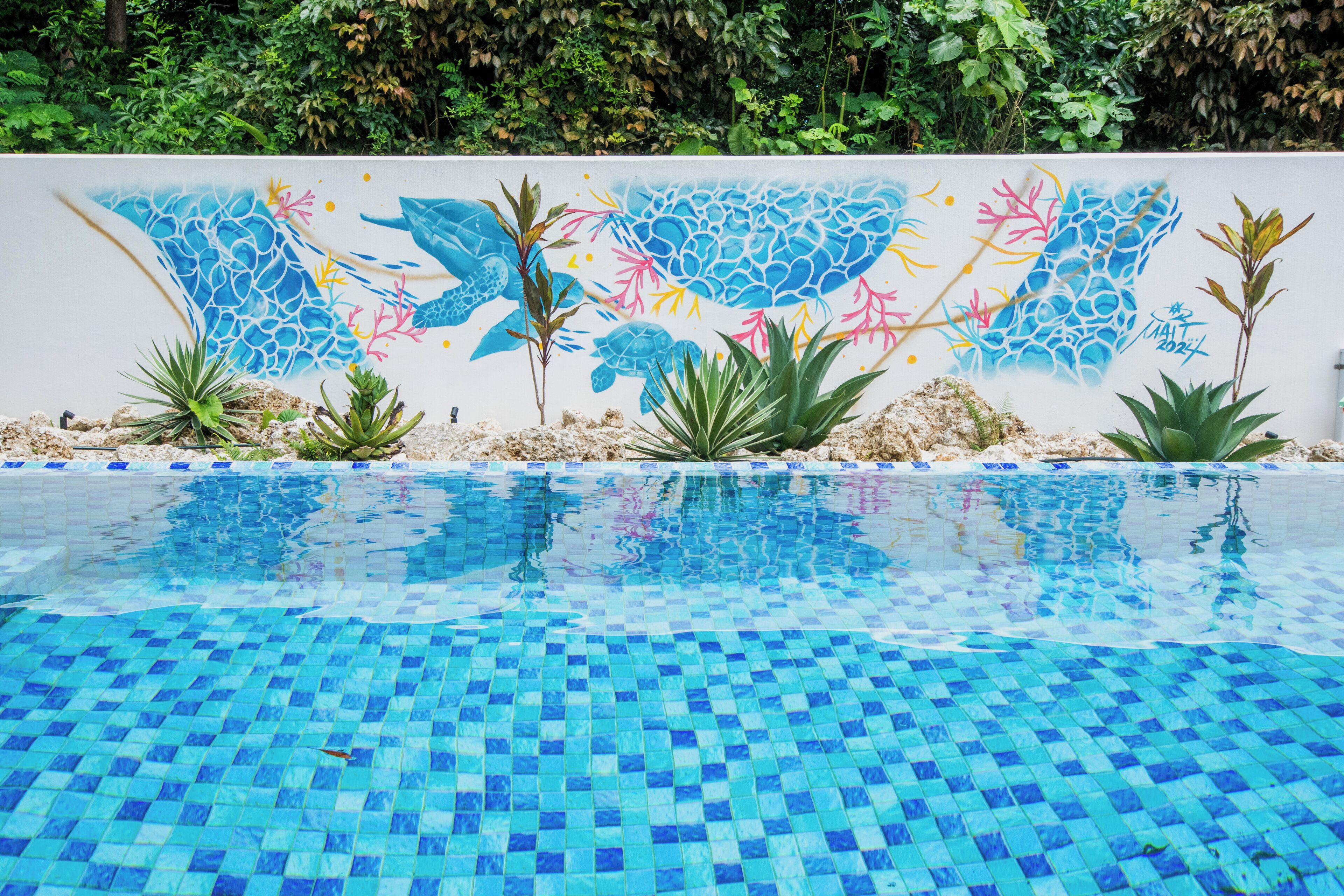 Una piscina con piso de baldosas y un mural con vida marina.