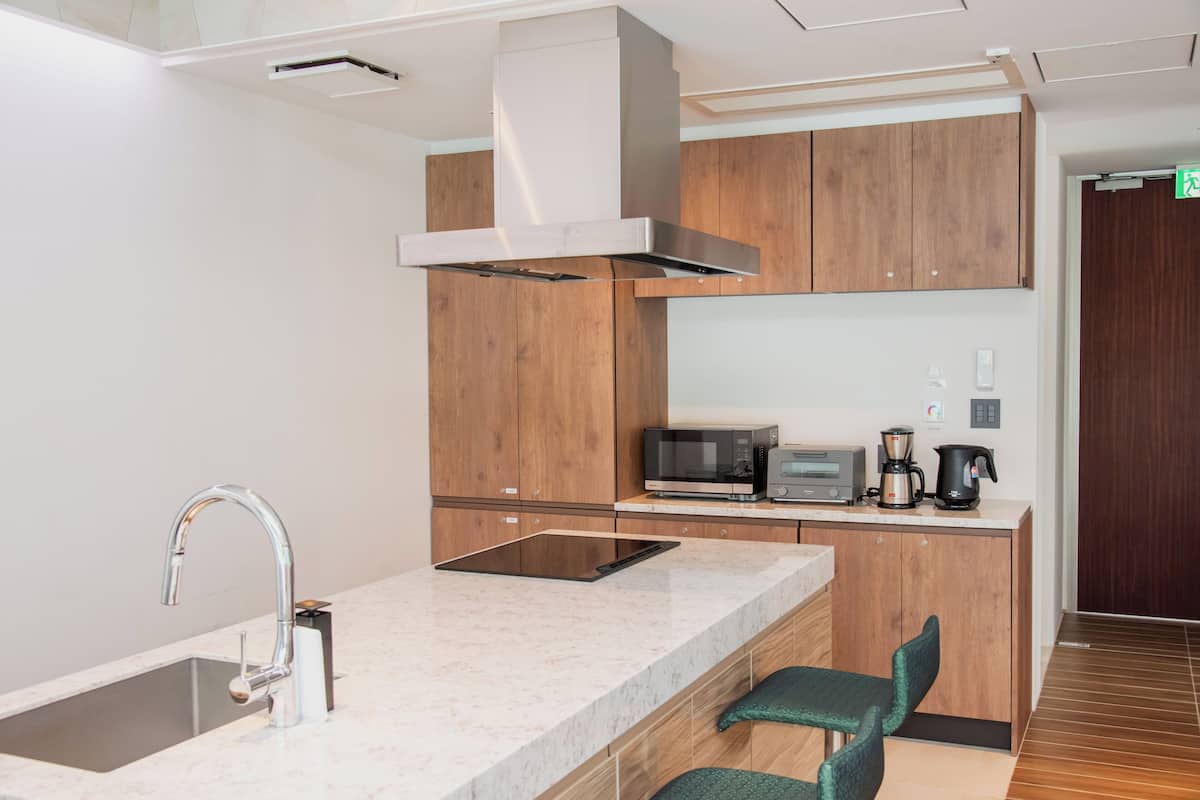 A modern kitchen with a built-in microwave, coffee maker, and a stainless steel range hood.