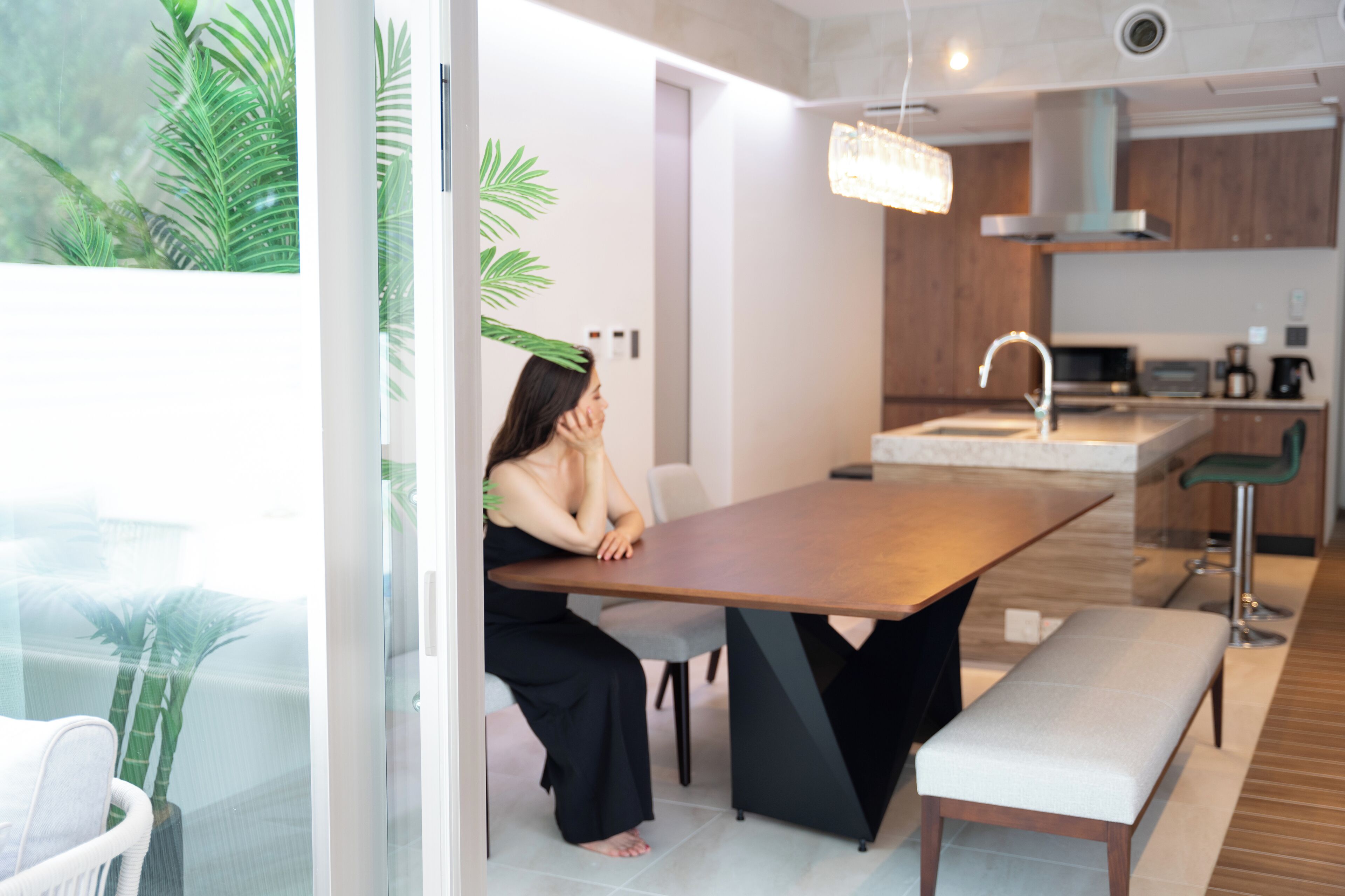 A modern kitchen with a wooden dining table, a bench, and a bar stool.