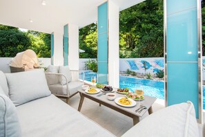 A modern outdoor dining area with a pool view, white furniture, and a clear sky. - pool villa Sanrriott Okinawa Motobu (Motobu)