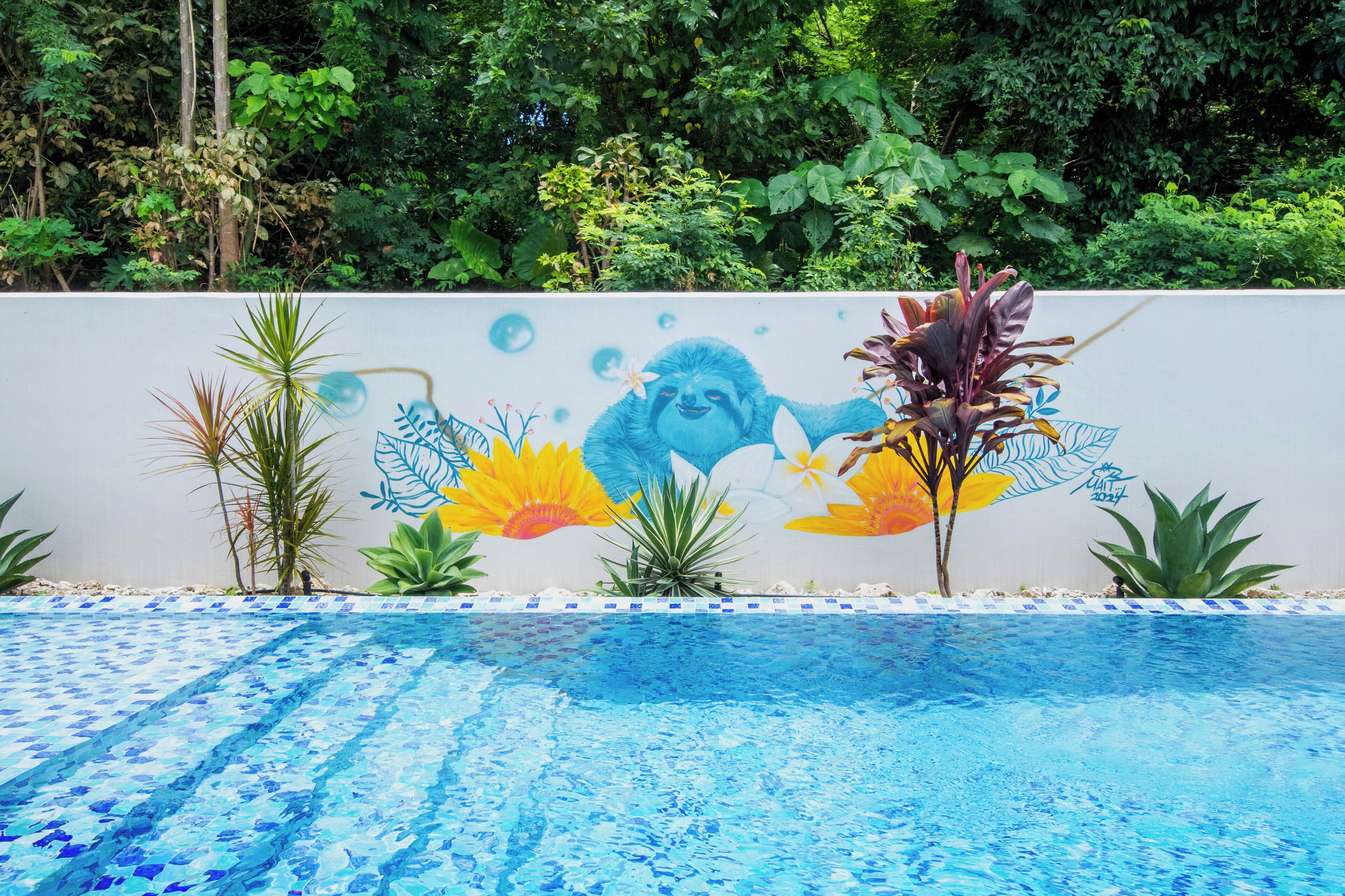 A swimming pool with a mural of a blue creature and tropical plants.