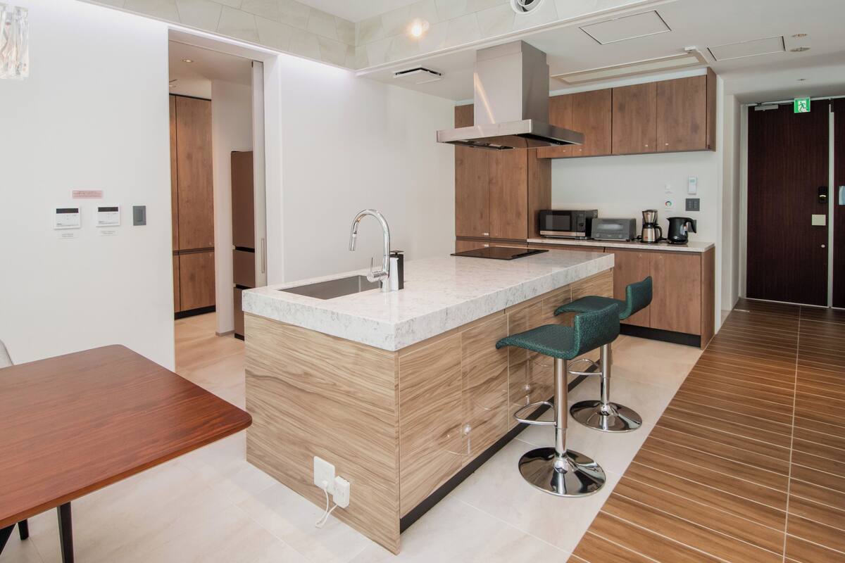 A modern kitchen with a central island, bar stools, and a microwave.