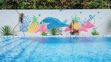 Una piscina con un mural de plantas tropicales y un ave.
