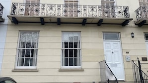 Ein mehrstöckiges Gebäude mit einem Balkon, der mit aufwendigen Metallgeländern und einer weißen Tür versehen ist.