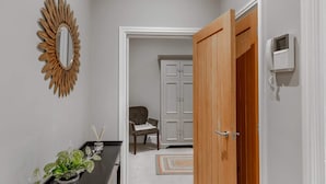 Ein Flur mit einer Holztür, einem weißen Schrank, einem Stuhl und einem Blumentopf.