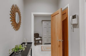 A hallway with a wooden door, a white cabinet, a chair, and a potted plant.