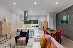 Una sala de estar moderna con un sofá, una mesa de comedor y una cocina al fondo.