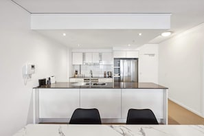 A modern kitchen with a central island, stainless steel appliances, and a dining area with two chairs.