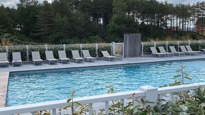 A swimming pool with lounge chairs and a wooden deck.