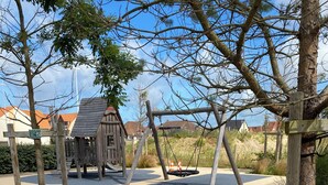 A playground with a swing set and a small wooden structure.