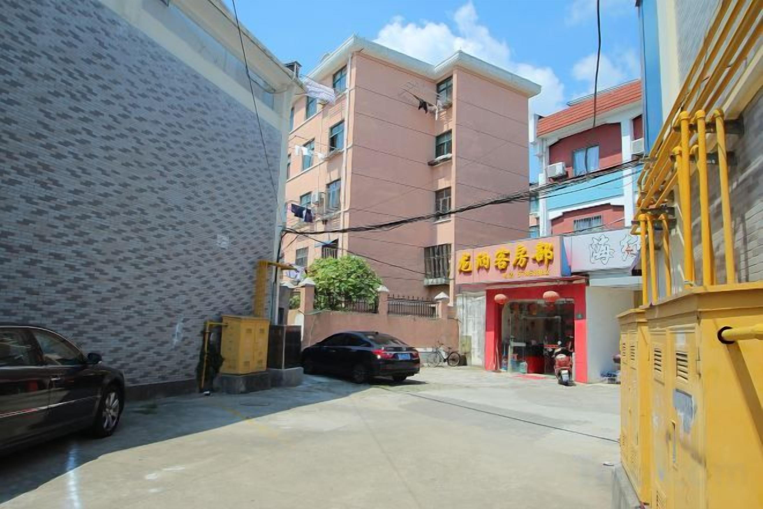 Une rue étroite, bordée de bâtiments des deux côtés, avec une voiture garée et une devanture de magasin surmontée d’un auvent rouge.