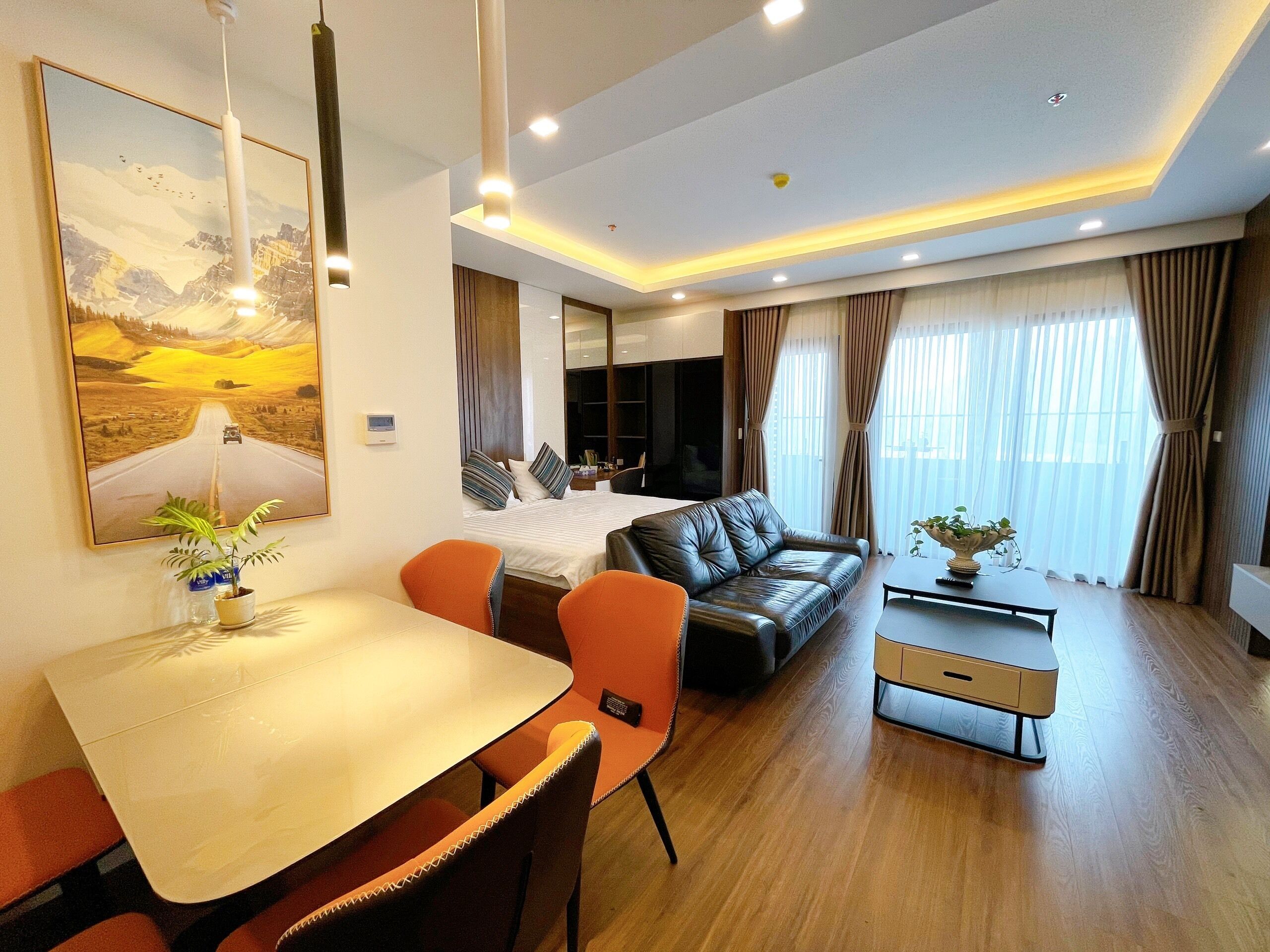 Quarto de hotel moderno com área de refeições, sofá e cama.