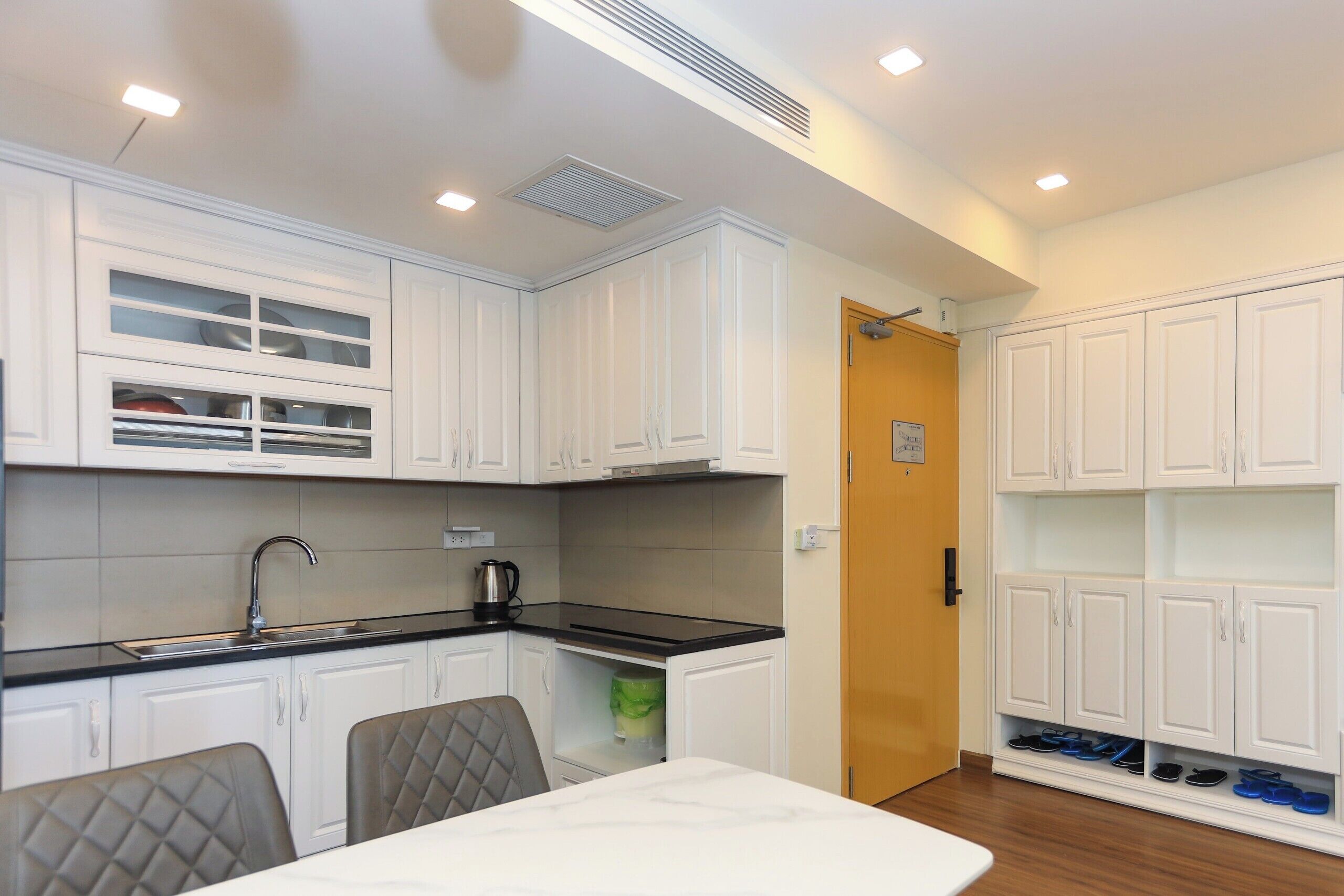 A compact kitchen with white cabinetry, a black countertop, and a dining area with a table and chairs.