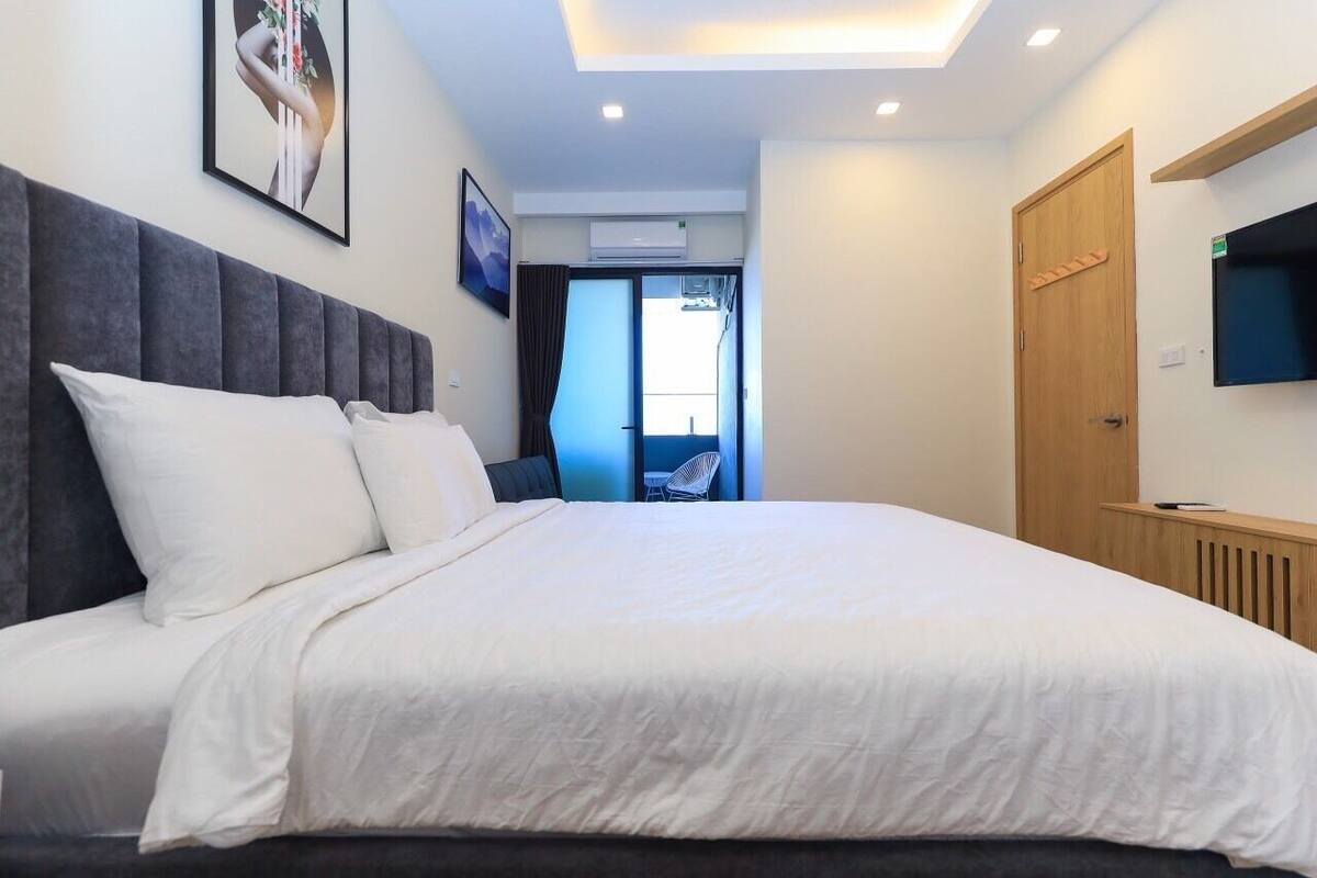 Ein modernes Hotelzimmer mit einem großen Bett, einem flachbildfernseher an der Wand und einer Tür zu einem Balkon.