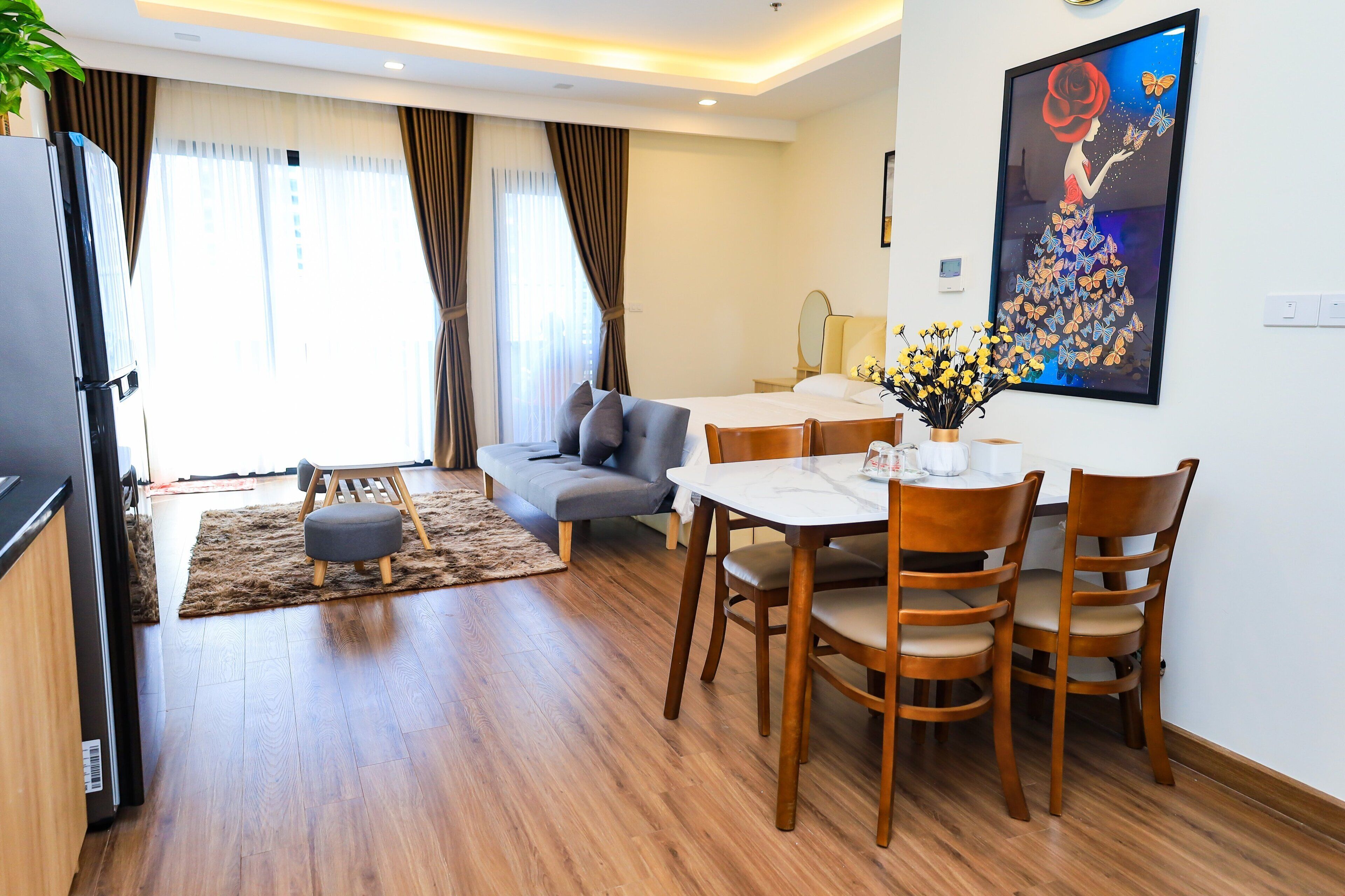 A modern hotel room with a dining area, a sofa, a table with chairs, and a painting on the wall.